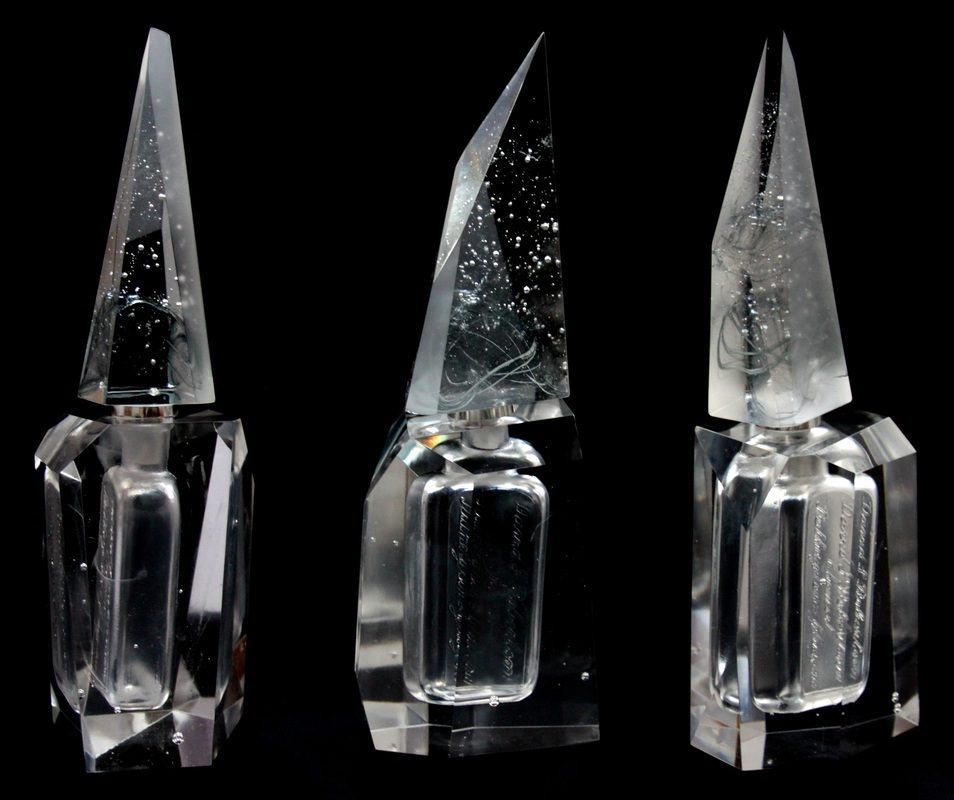 Aura — three faceted glass perfume bottles with pointed stoppers