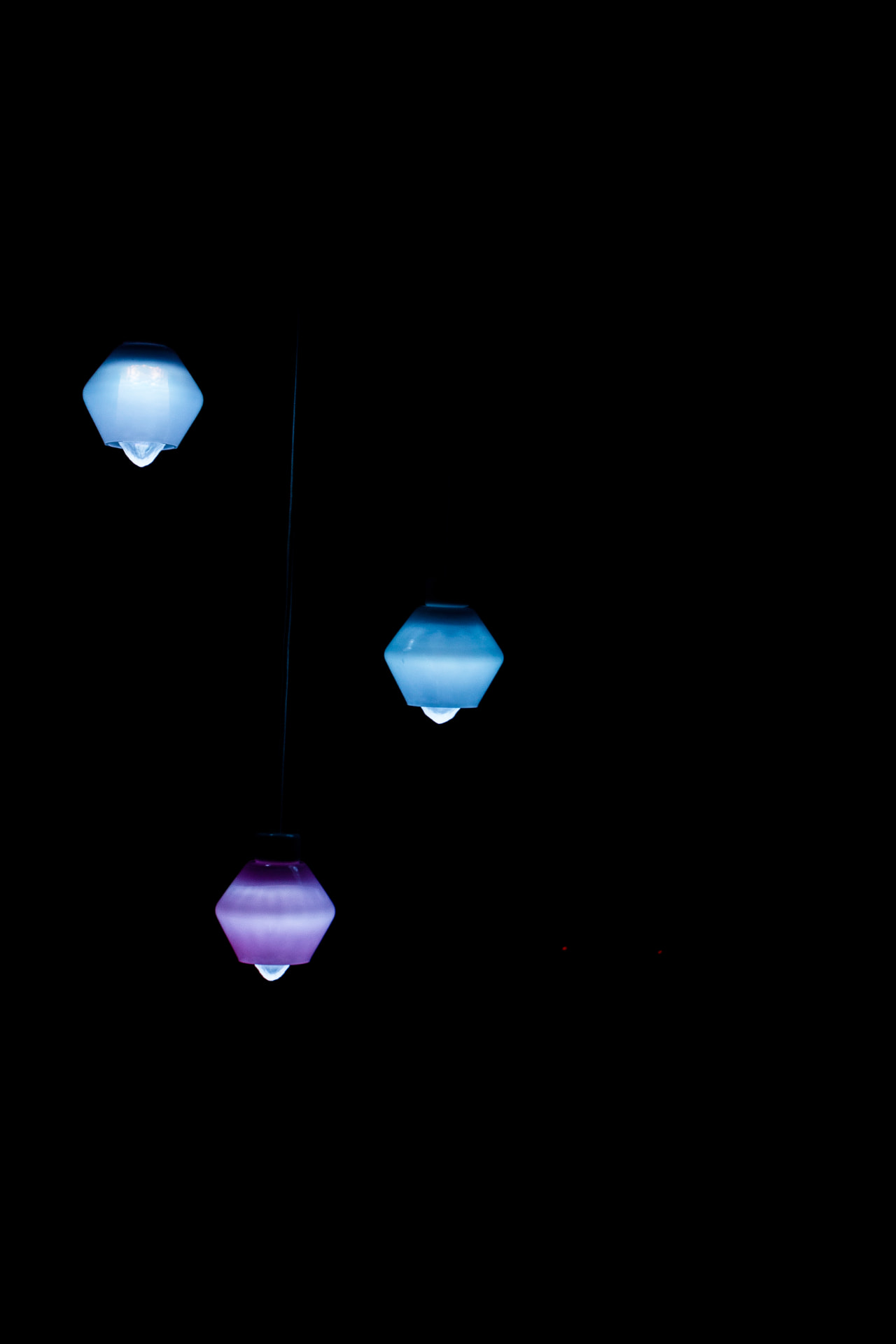 Jewel Lamps — three pendant lights in blue and violet suspended in darkness