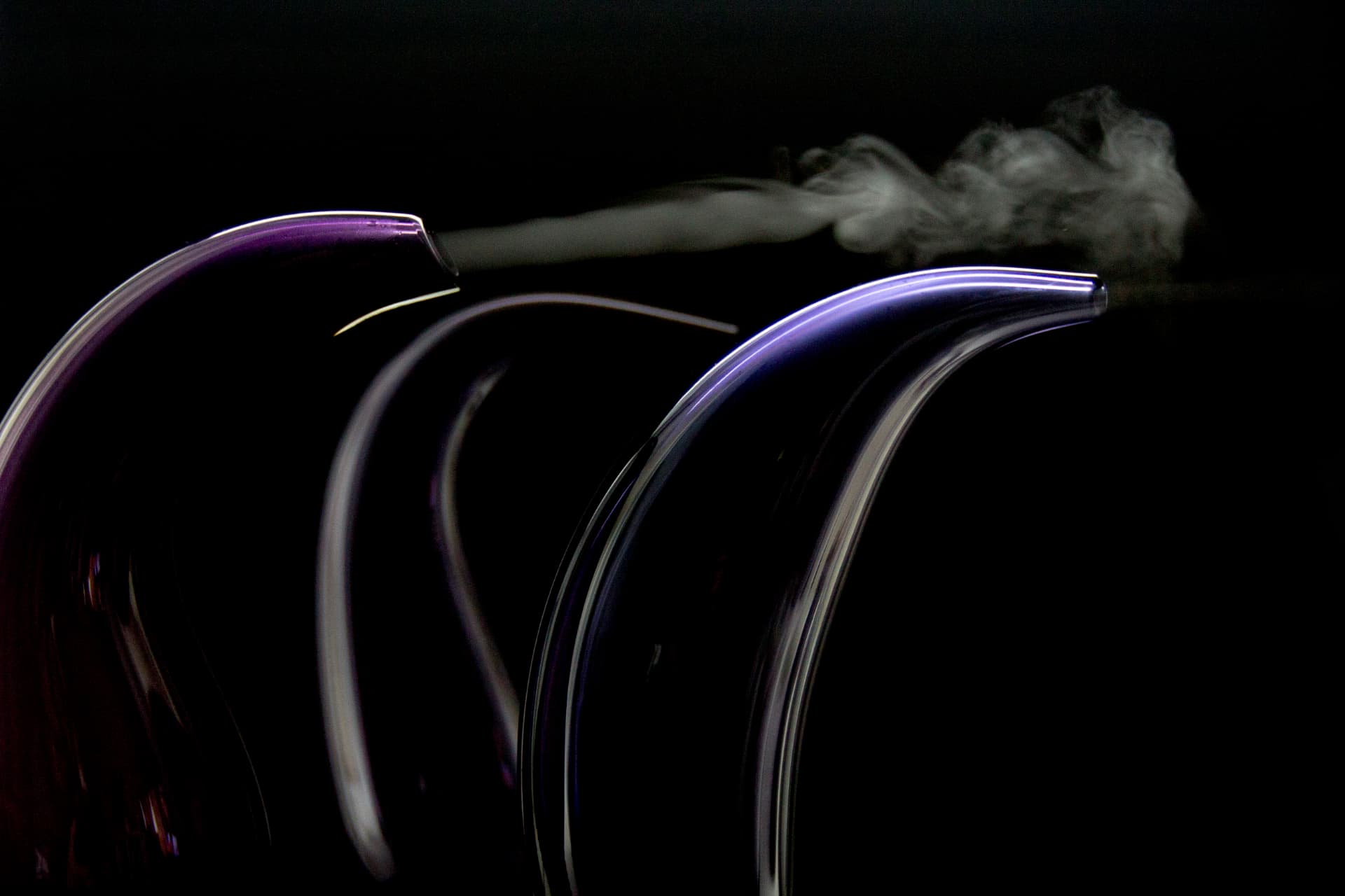 Fluidity — scent drifting from the open end of a curved blown glass form against black