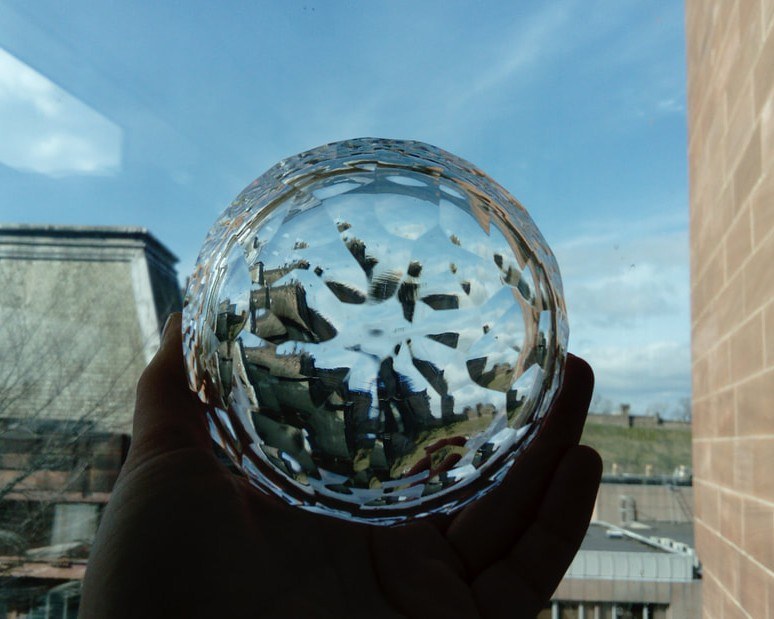 The cut crystal held against a bright sky, the city refracted within